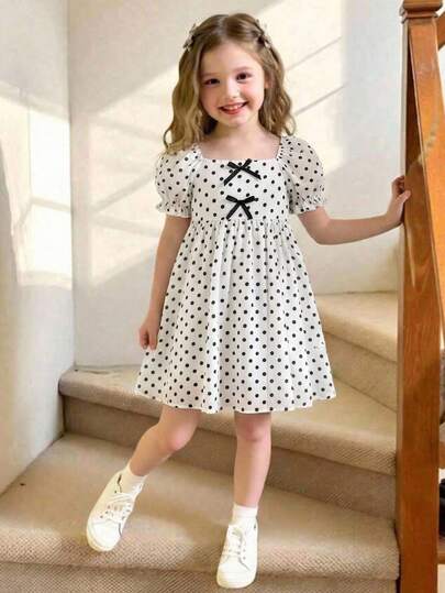 Robe à col carré, manches bouffantes et volants tressés pour jeune fille. Robe courte à manches courtes pour filles. Robe jeune fille crème et noire à pois avec nœud