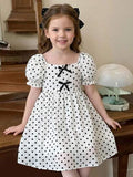 Robe à col carré, manches bouffantes et volants tressés pour jeune fille. Robe courte à manches courtes pour filles. Robe jeune fille crème et noire à pois avec nœud